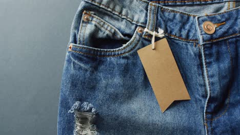 Close-up-of-jeans-with-tag-on-grey-background-with-copy-space