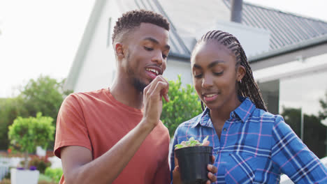 Happy-african-american-couple-with-plant-sprout-in-backyard