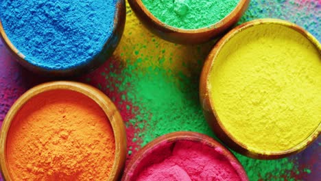 Video-of-close-up-of-multi-coloured-powders-in-bowls-with-copy-space-on-black-background