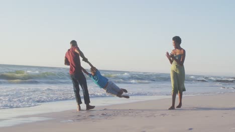 Video-of-happy-african-american-family-having-fun-on-beach-at-sunset
