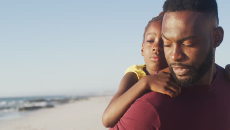 Video-Eines-Afroamerikanischen-Vaters,-Der-Seine-Tochter-Huckepack-Am-Strand-Trägt