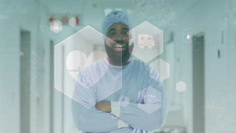 Animation-of-medical-icons-over-portrait-of-smiling-african-american-male-doctor-in-corridor