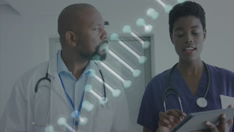 Animation-of-dna-strand-over-african-american-female-and-male-doctor-with-tablet-talking-in-hospital