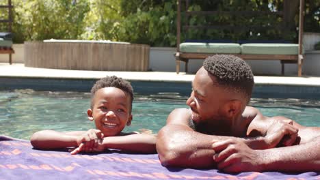 Glücklicher-Afroamerikanischer-Vater-Und-Sohn-Am-Pool,-In-Zeitlupe