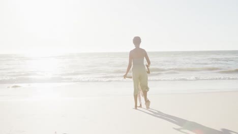 Happy-african-american-mother-and-daughter-walking-at-beach,-in-slow-motion