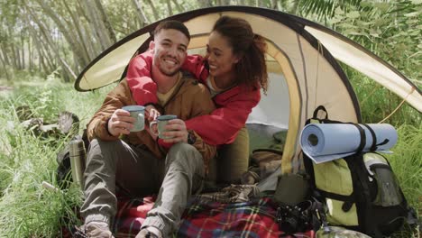 Portrait-of-happy-african-american-couple-camping,-drinking-coffee-in-forest,-slow-motion