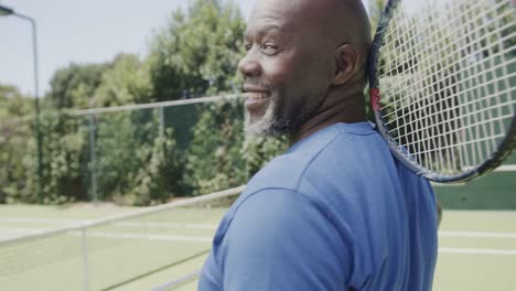 Portrait-of-happy-senior-african-american-man-playing-tennis-at-tennis-court-in-slow-motion