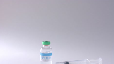 Close-up-of-insulin-vial-and-syringe-on-grey-background-with-copy-space,-slow-motion