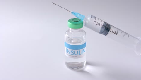 Close-up-of-insulin-vial-and-syringe-on-white-background-with-copy-space,-slow-motion