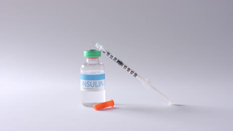 Close-up-of-insulin-vial-and-syringe-on-grey-background,-slow-motion