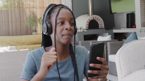 Happy-african-american-teenage-girl-with-headphones-listening-to-music-with-smartphone