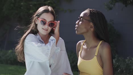 Happy-diverse-teenage-female-friends-wearing-sunglasses-talking-in-sunny-garden-in-slow-motion