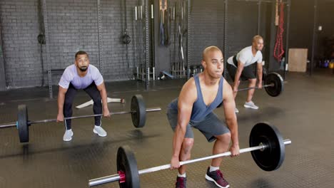 Diverse-male-group-lifting-barbells,-free-weight-training-at-gym,-in-slow-motion