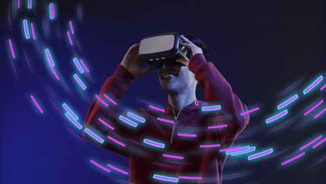 Animation-of-glowing-light-trails-of-data-transfer-over-asian-man-using-vr-headset