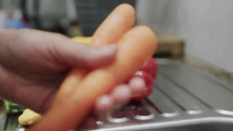 Hands-of-biracial-woman-washing-carrots-in-kitchen-sink,-slow-motion