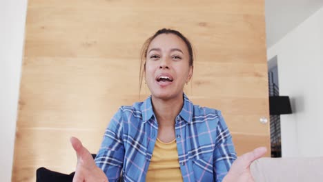 Emotional-biracial-woman-making-video-call-talking-and-gesturing-in-living-room,-in-slow-motion