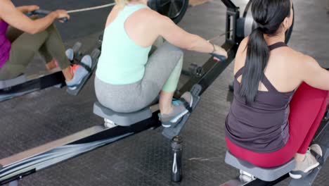 Determined-unaltered-diverse-women-exercising-on-rowing-machines-at-gym,-in-slow-motion