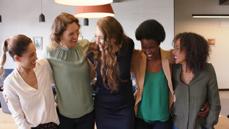 Portrait-of-happy-diverse-businesswomen-standing-in-office-embracing-and-smiling,-in-slow-motion