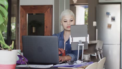 Busy-biracial-woman-working-at-home-with-laptop-and-tablet-in-slow-motion