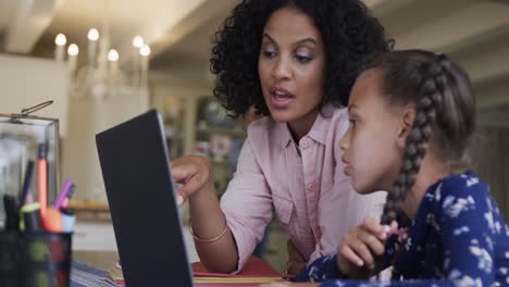 Glückliche-Gemischtrassige-Mutter-Und-Tochter-Lernen-Online-Mit-Laptop-Am-Tisch,-Zeitlupe