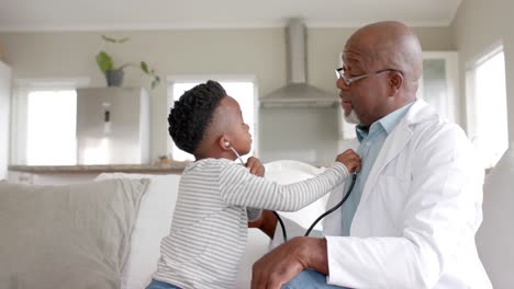 African-american-boy-patient-using-stethoscope-on-doctor-at-home,-slow-motion