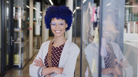Portrait-of-happy-biracial-businesswoman-with-blue-afro-in-office,-slow-motion