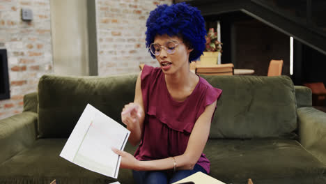 Biracial-businesswoman-with-blue-afro-having-video-call-in-office,-slow-motion