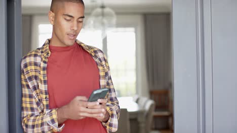 Hombre-Birracial-Feliz-Usando-Un-Teléfono-Inteligente-En-Casa,-Cámara-Lenta