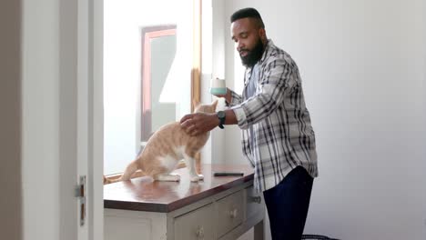 Hombre-Afroamericano-Tomando-Café-Y-Acariciando-A-Un-Gato-En-Casa,-Cámara-Lenta