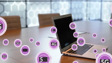 Animation-of-5g-text-and-symbols-in-circles-over-laptop-on-table-against-hexagon-pattern-on-window