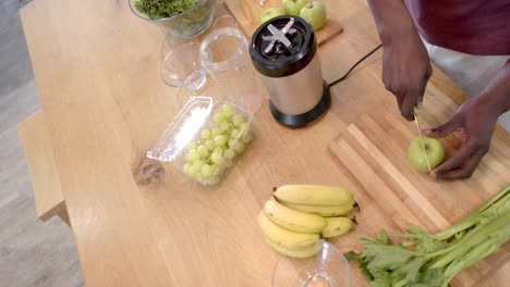 Midsection-of-african-american-man-preparing-healthy-smoothie-in-kitchen-at-home,-slow-motion