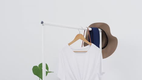 Video-of-white-t-shirt-on-hanger-with-hat-and-copy-space-on-white-background