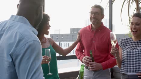 Team-of-diverse-happy-colleagues-having-drinks-and-talking-to-each-other-in-the-balcony-at-office