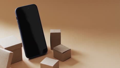 Video-of-smartphone-with-blank-screen-and-boxes-with-copy-space-on-orange-background