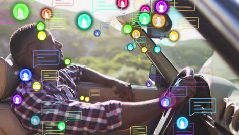 Animation-of-icons,-speech-bubbles,-african-american-man-holding-steering-wheel-and-sitting-in-car