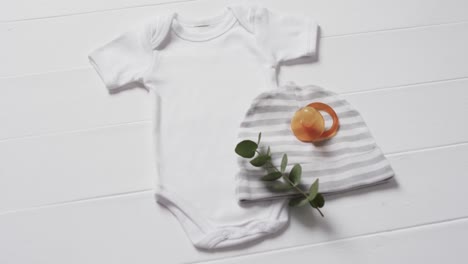 Video-of-white-baby-grow,-hat-and-dummy-with-copy-space-on-white-background