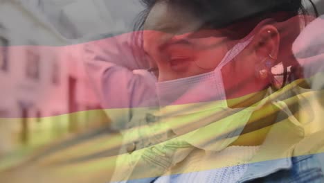 Animation-of-waving-germany-flag-against-asian-woman-wearing-face-mask-on-the-street