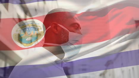 Animation-of-waving-costa-rica-flag-over-african-american-man-wearing-face-mask-on-the-street