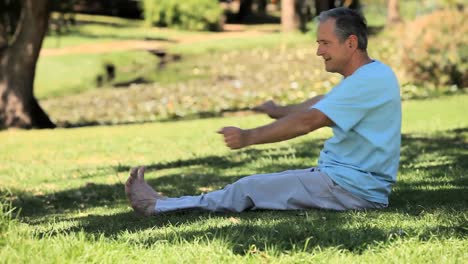 Elderly-male-doing-warm-up-sitting-on-the-grass
