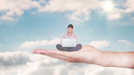 Hand-holding-sitting-businesswoman-focused-on-laptop-against-blue-sky