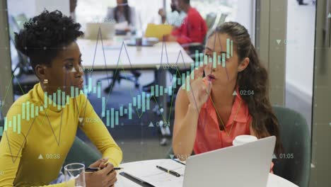 Animation-of-data-processing-against-two-diverse-women-discussing-over-a-laptop-at-office