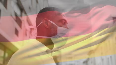 Animation-of-waving-germany-flag-against-african-american-man-wearing-face-mask-on-the-street