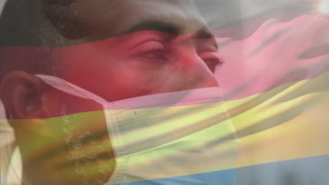 Animation-of-waving-germany-flag-against-close-up-of-african-american-man-in-face-mask-on-the-street