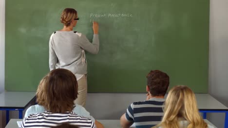 Teacher-writing-on-blackboard-in-class