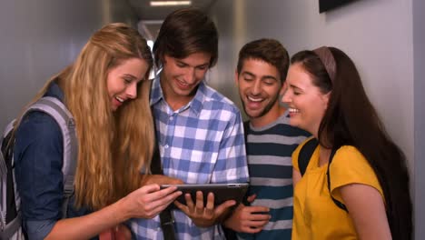 Students-looking-at-tablet-pc-in-the-hall-at-the-university-