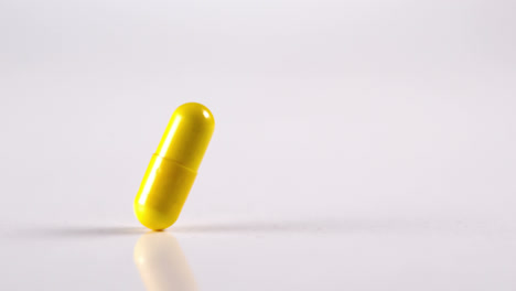 One-yellow-medication-falling-against-white-background