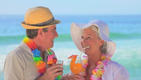 Mature-couple-wearing-garlands-drinking-fruit-cocktails