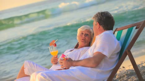 Mature-couple-drinking-cocktails-in-deckchairs