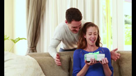 Man-surprising-his-girlfriend-with-a-gift-on-the-couch