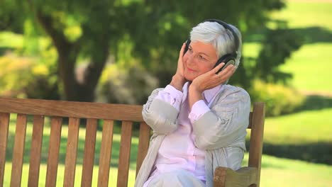 Elderly-woman-listening-to-music-on-a-bench